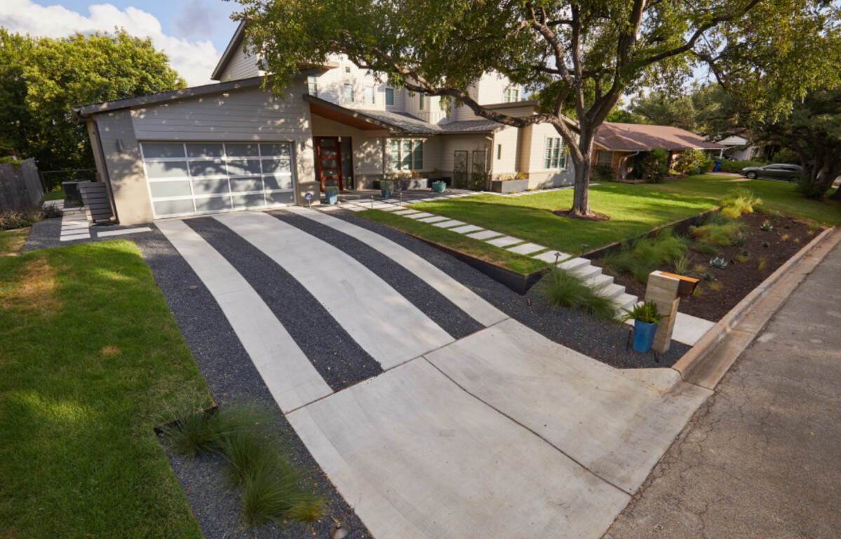 Modern concrete driveway with decorative black gravel strips in Bradenton, FL